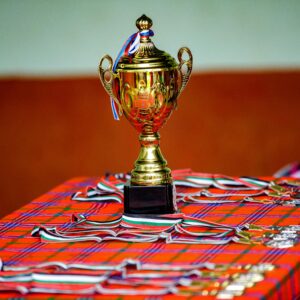 Golden trophy with ribbons and medals on a checkered table, symbolizing victory and achievement.