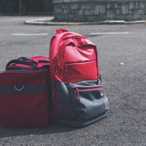 Red backpack and matching bag on asphalt, perfect for travel themes.