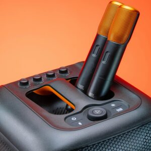 Modern JBL speaker featuring two wireless microphones, set against a vibrant orange background.