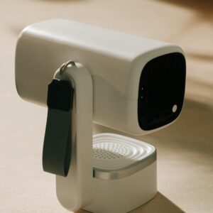 Sleek white portable projector with a strap, perfect for home or travel use.