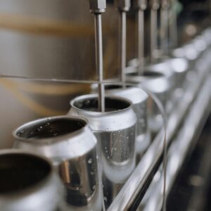 Detailed view of an industrial canning process with aluminum cans on an automatic assembly line.