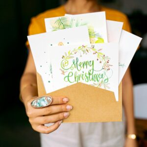 A close-up view of hands holding decorative Christmas cards in an envelope.