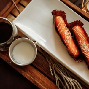 A stylish flatlay of pastries with coffee and milk on a wooden tray, perfect for breakfast.